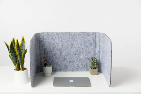 Hide privacy screen, using charcoal colored PET. A laptop is closed, with a few small plants in front of it.