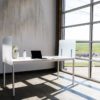 Simple table desk placed at the window in an office. Shelter screens lines the sides of the desk, and a laptop sits with its lid open.