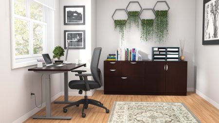 Studio shot of OTG's Home Office Setup, which has a height-adjustable work desk placed at the window. A set of four planters is hung on the wall, above the mixed storage unit. Both surfaces are finished in an American Espresso. A total of four drawers and a double-door cabinet can store different supplies. On top is a set of books, with a giraffe bookend sculpture. A file box to the right holds two columns of slots for important files or as an Inbox.