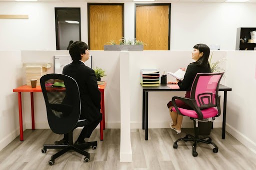 Two colleagues talking to each other in their cubicles 